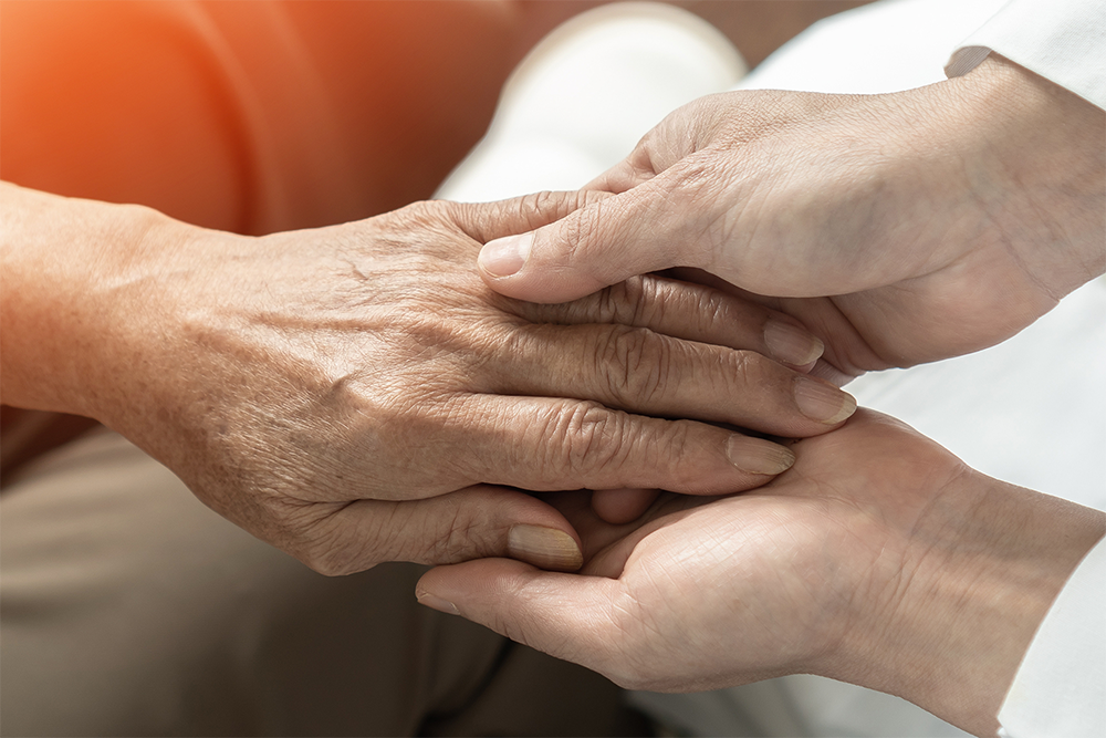 A doctors hands holding the hand of a patient